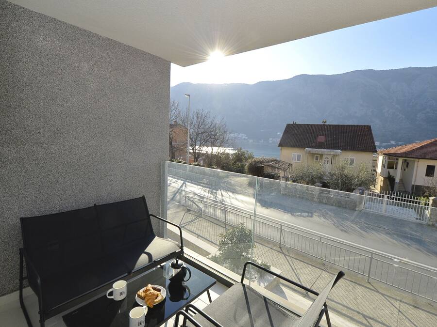 A balcony with a table, chairs, and a view of a mountain and lake.