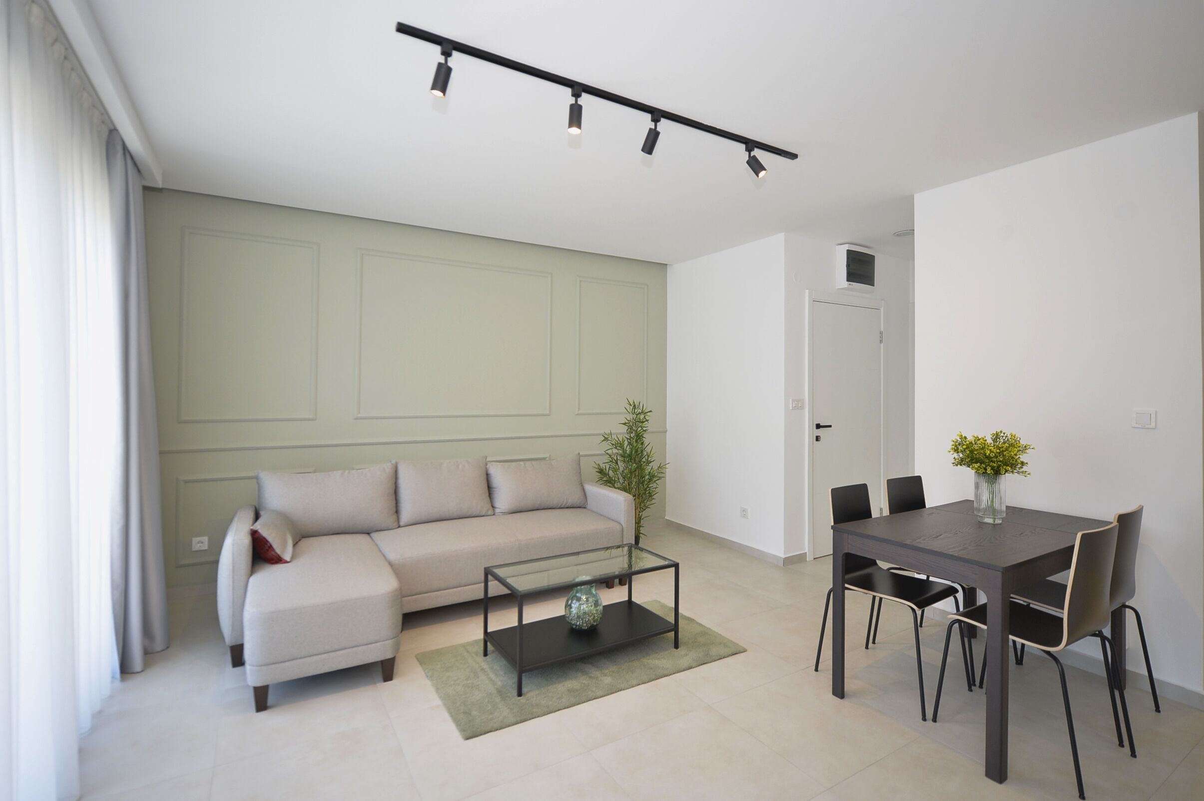 Een moderne woonkamer met een bank, salontafel en eettafel.
