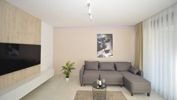 Departamento Deluxe, 1 cama Queen size y sofá cama, balcón, vista a la bahía | Área de sala de estar | Smart TV de 55 pulgadas con canales digitales, televisión y Netflix