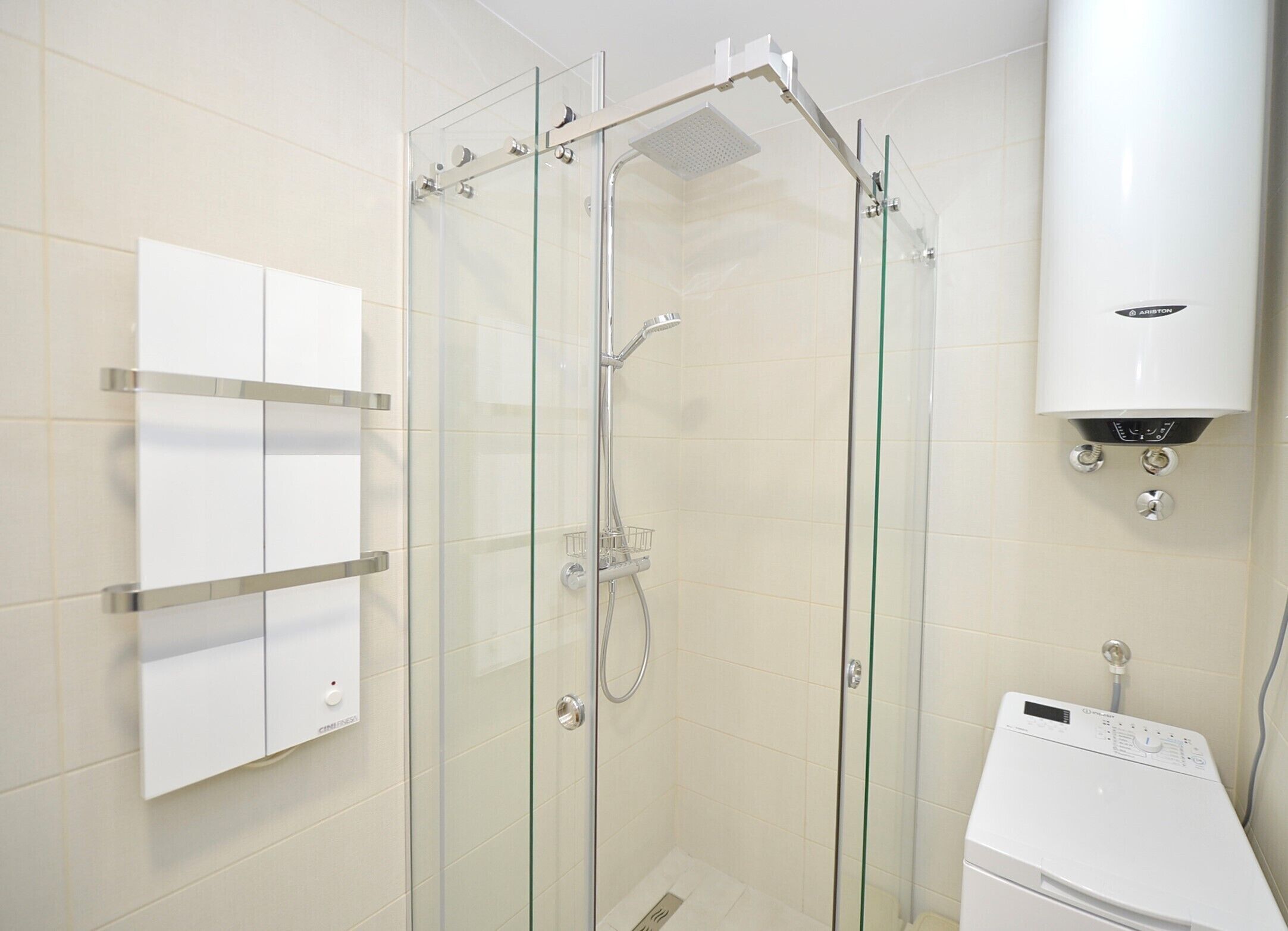 A glass-enclosed shower with a control panel, a white toilet, and a wall-mounted heater.
