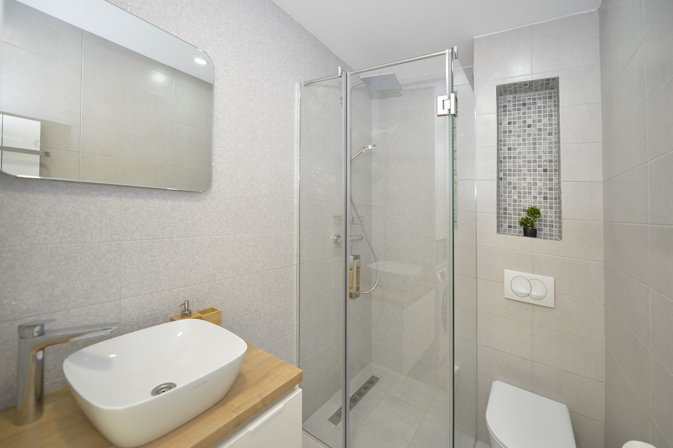 A modern bathroom with a glass-enclosed shower, a white sink, and a toilet.