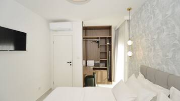 A hotel room with a bed, a wardrobe, a desk, and a TV mounted on the wall.