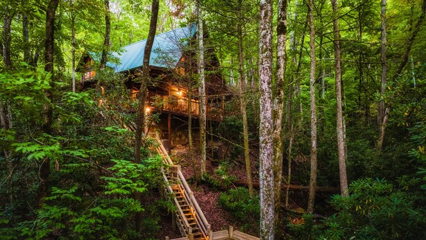 Una baita nel bosco con una scala in legno che porta a un terrazzo.