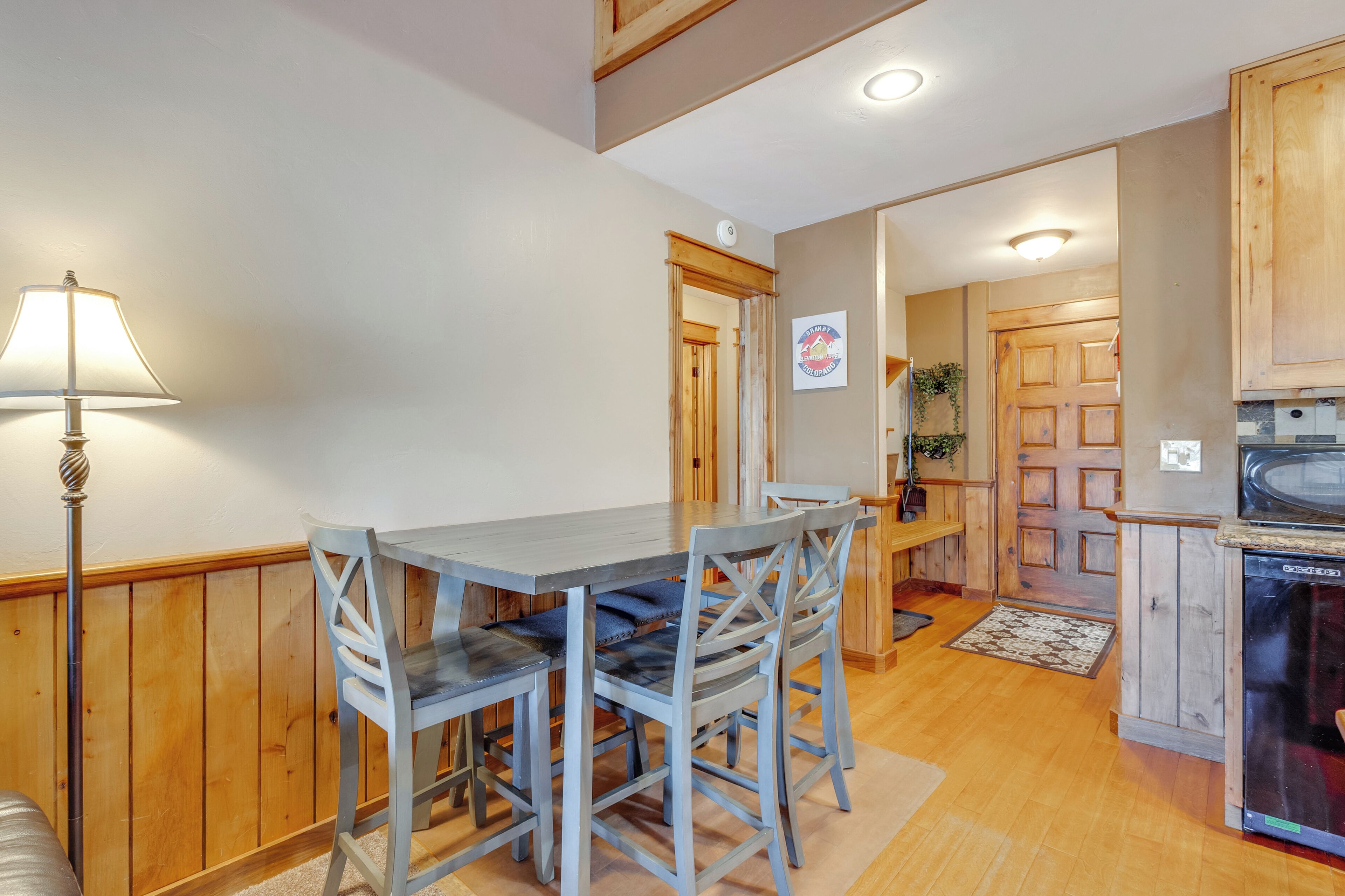 A dining area with a table and chairs, wooden walls, and a kitchen with wooden cabinets.