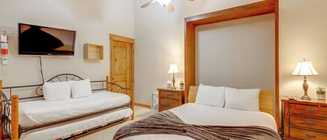 Habitación de hotel con dos camas individuales, un espejo grande, un ventilador de techo, un televisor y lámparas de noche.