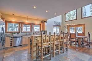 A spacious kitchen with wooden bar stools, a dishwasher, and large windows offering views of a snowy landscape. - Breckenridge 'sky Lodge' w/ Hot Tub + Gas Grill! (Breckenridge)