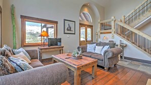 A spacious living room with a wooden coffee table, two sofas, a television, and a staircase.