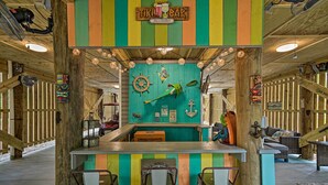 A tiki bar with a wooden interior, a bar counter, and three bar stools. - Quiet Fisherman's House w/ Hot Tub + Tropical Bar! (Dauphin Island)