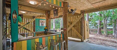 A wooden bar area with colorful vertical stripes, a wooden staircase, and a view of trees outside.