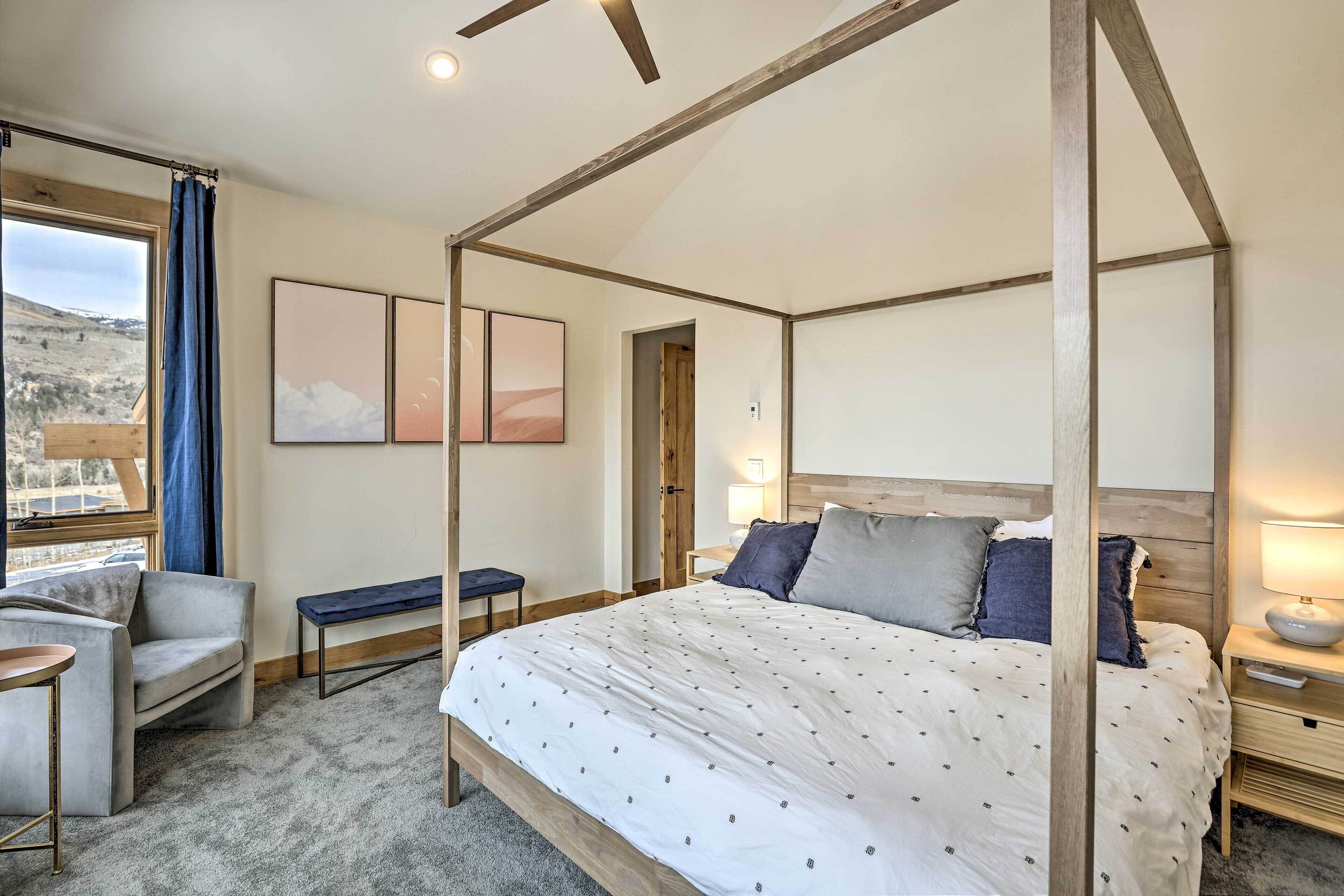 A bedroom with a four-poster bed, a bench, a chair, and a small table.