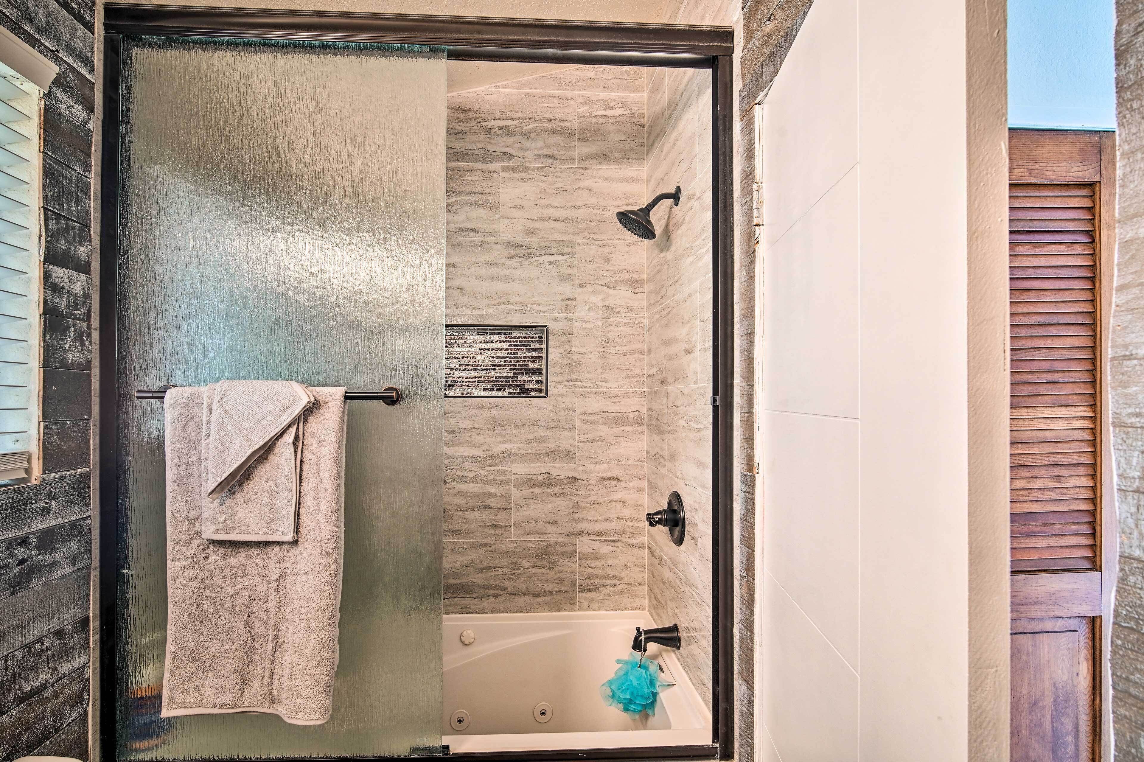 Ein modernes Badezimmer mit einer gläsernen Duschkabine, einer Badewanne und einem Handtuchhalter.