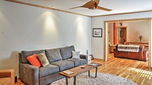 Ein modernes Wohnzimmer mit einem grauen Sofa, einem Holztisch und einem Deckenventilator.