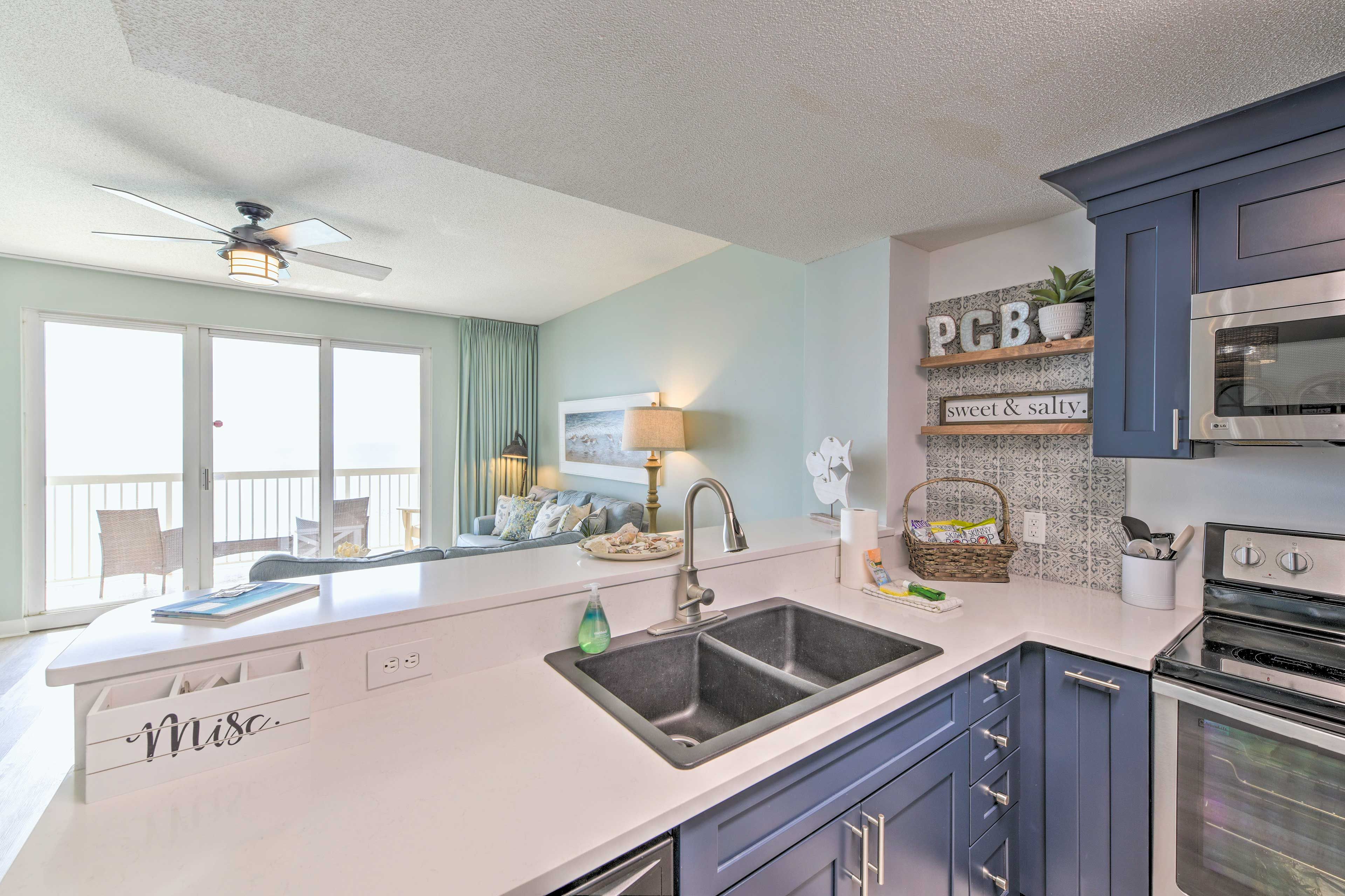 A modern kitchen with a white island, dark blue cabinets, and stainless steel appliances.