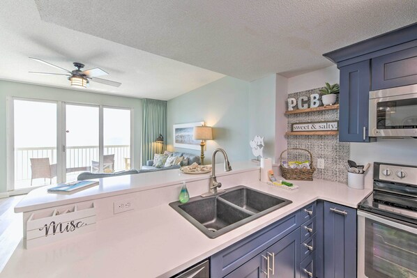 A modern kitchen with a white island, dark blue cabinets, and stainless steel appliances.