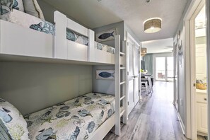 A room with bunk beds, a hallway, and a door leading to another room.