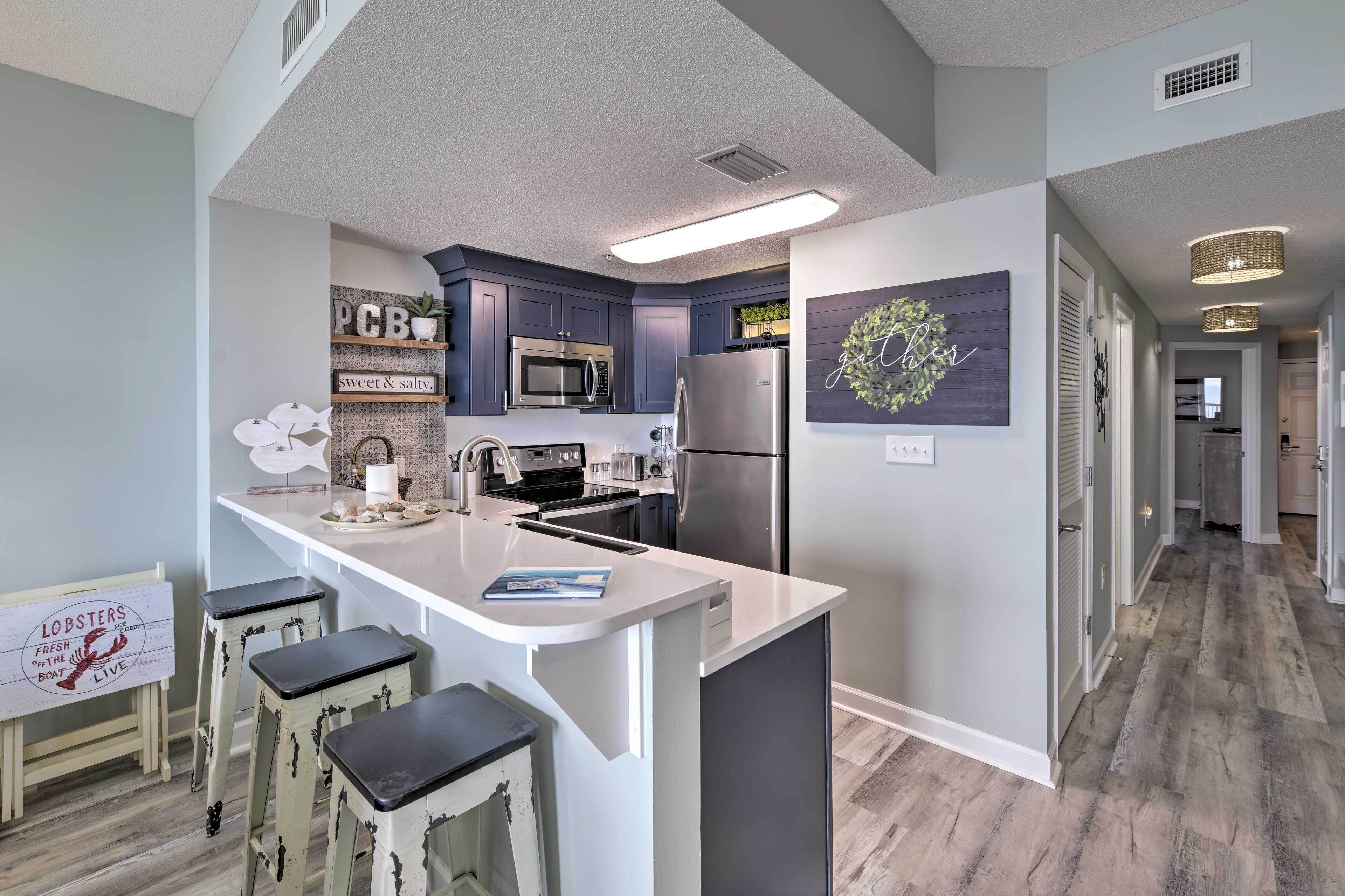 A modern kitchen with a central island, bar stools, a microwave, and a refrigerator.