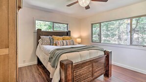 A bedroom with a wooden bed, large windows, and a ceiling fan. - Spacious Lake Arrowhead Cabin w/ Jacuzzi Spa! (Lake Arrowhead)