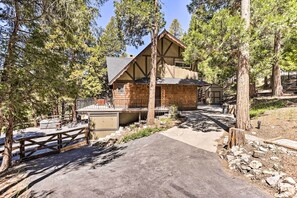 A lodge with a rustic design, a covered patio, and a dirt path leading to the entrance.
