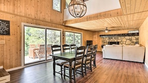 A wooden interior with a dining table and chairs, a sofa, and a stone fireplace. - Spacious Lake Arrowhead Cabin w/ Jacuzzi Spa! (Lake Arrowhead)