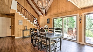 A dining area with a wooden table and chairs, a chandelier, and a staircase leading to another level. - Spacious Lake Arrowhead Cabin w/ Jacuzzi Spa! (Lake Arrowhead)