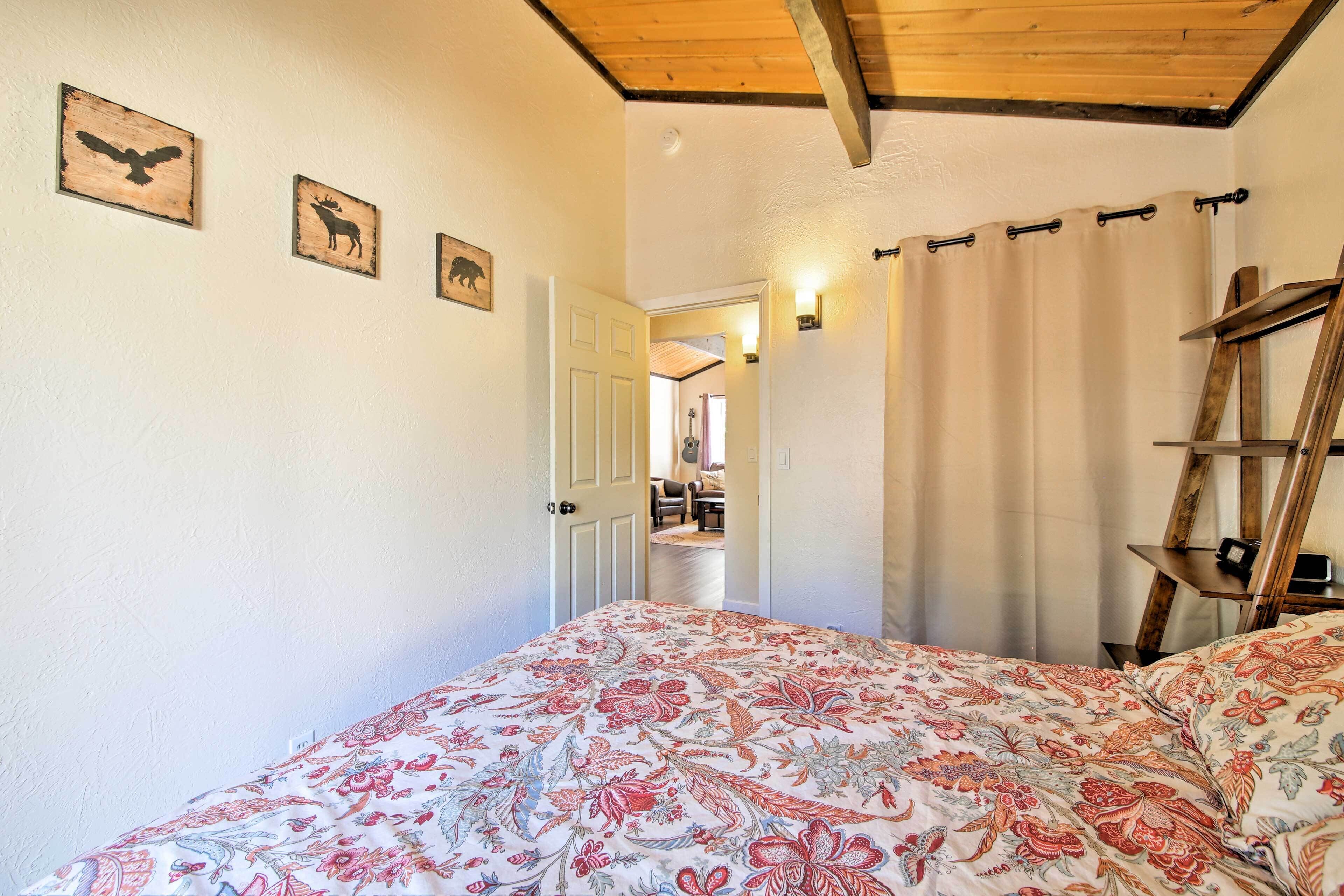 A bedroom with a floral bedspread, a wooden ladder, and wall-mounted animal-themed artwork.