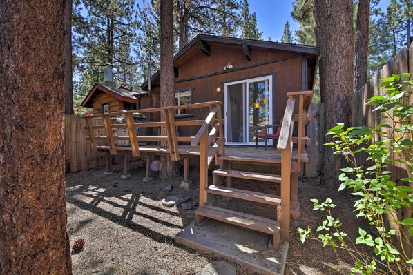 A rustic cabin with a wooden deck and stairs leading to a glass door.