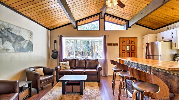 A cozy living room with a brown leather sofa, a coffee table, and a wooden ceiling.