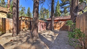 A backyard with a wooden fence, a basketball hoop, and a shed.