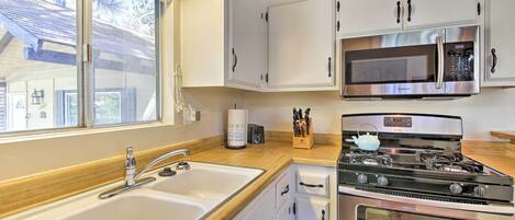A kitchen with a double sink, stainless steel appliances, and white cabinetry.