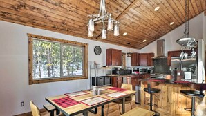 A spacious kitchen with wooden cabinets, a large window, and a dining area with a wooden table and chairs. - Luxury Mountain Getaway in Fairplay w/ Deck! (Fairplay)