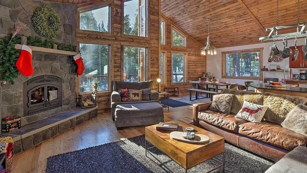 A spacious log cabin interior with a stone fireplace, large windows, and a cozy seating area. - Luxury Mountain Getaway in Fairplay w/ Deck! (Fairplay)