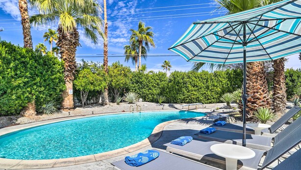 A swimming pool with lounge chairs and an umbrella. - Pool & Mountain Views: Palm Springs Home! (Palm Springs)