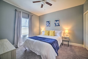 A bedroom with a bed, bedside tables, a ceiling fan, and artwork on the wall.