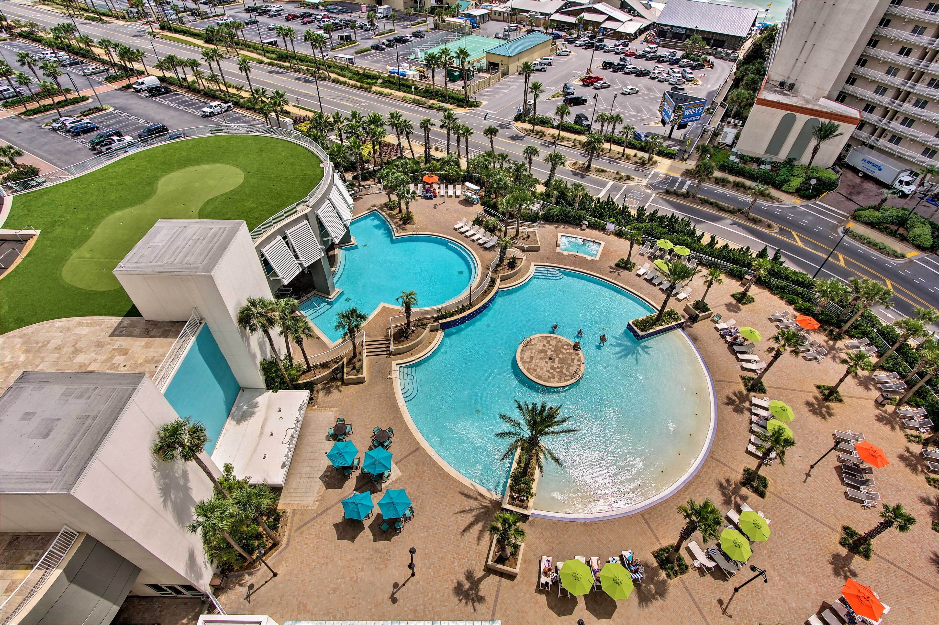 A hotel with a large swimming pool, multiple lounge areas, and a landscaped garden.