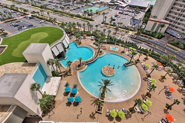 A hotel with a large swimming pool, multiple lounge areas, and a landscaped garden.