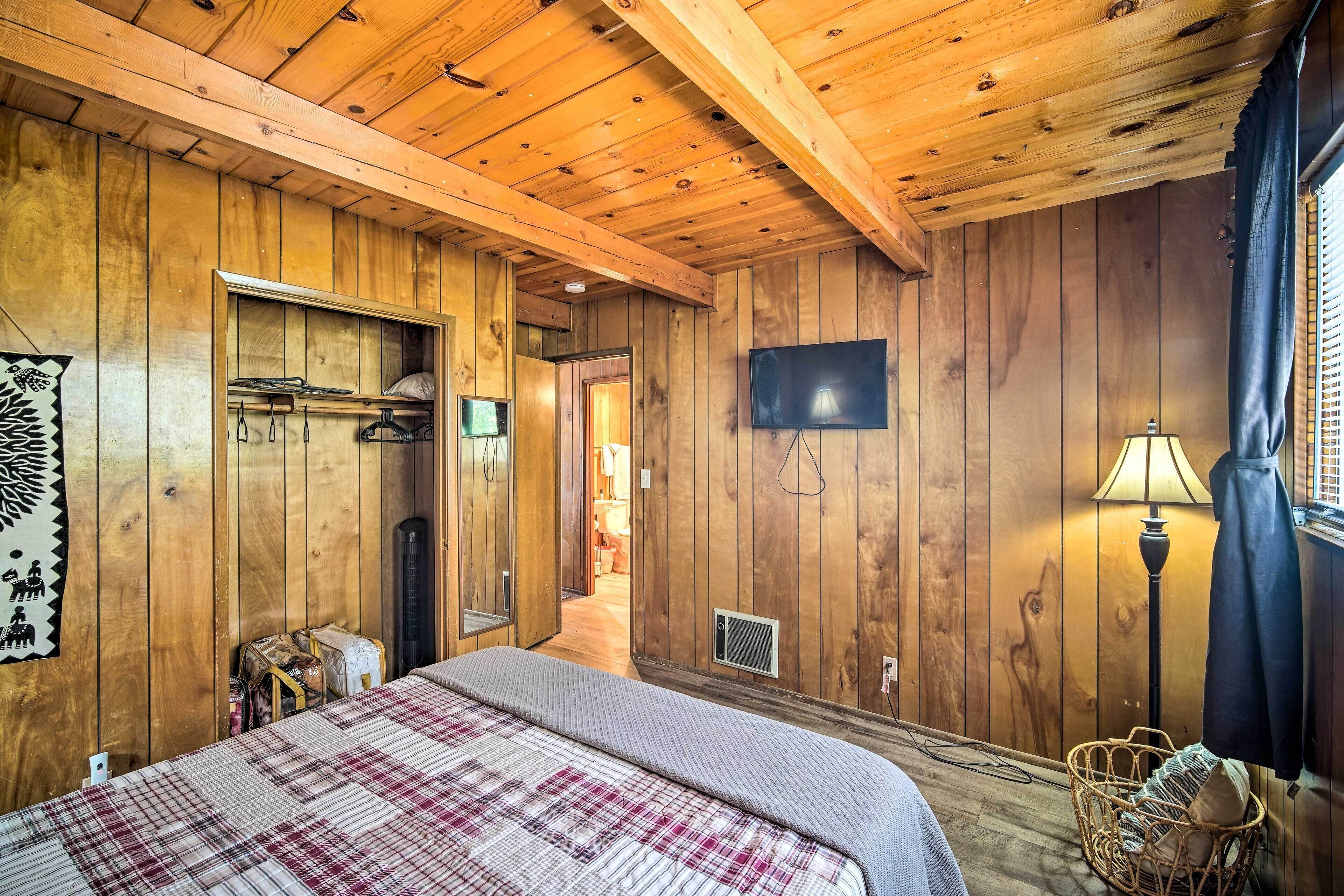 Ein Zimmer mit Holzwänden, einem Bett, einem Fernseher, einer Lampe und einem Korb.