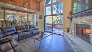Un salón espacioso con un sofá de cuero grande tipo seccional, una chimenea y ventanas amplias que ofrecen vistas al exterior.
