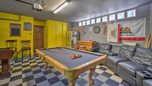 Una mesa de billar en una sala con paredes amarillas, una mesa de billar y un sofá.