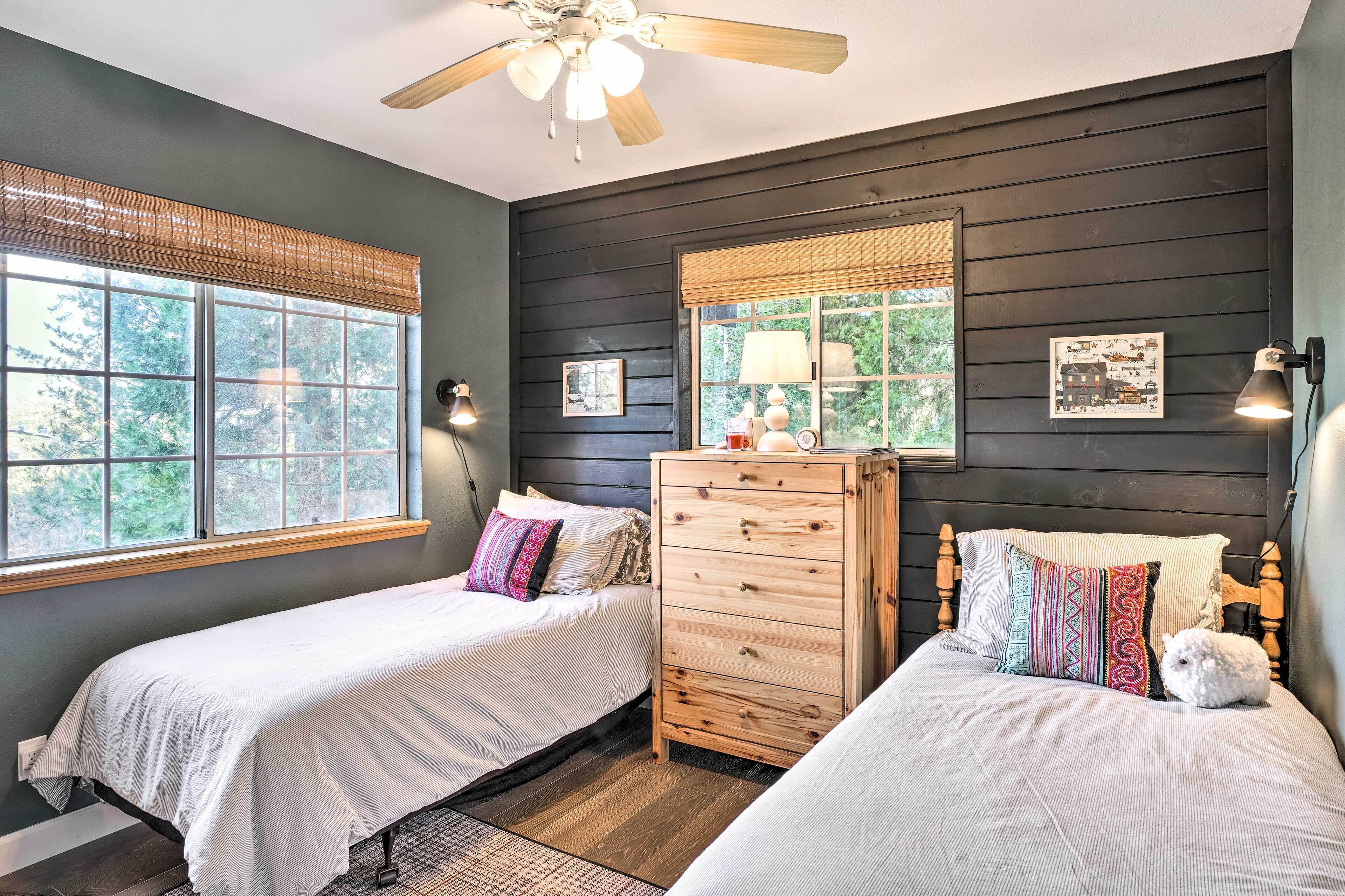 A bedroom with two beds, a dresser, and a ceiling fan.