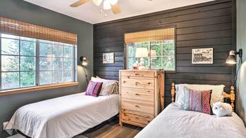 Une chambre avec deux lits, une commode et un ventilateur de plafond.
