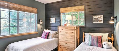 A bedroom with two beds, a dresser, and a ceiling fan.