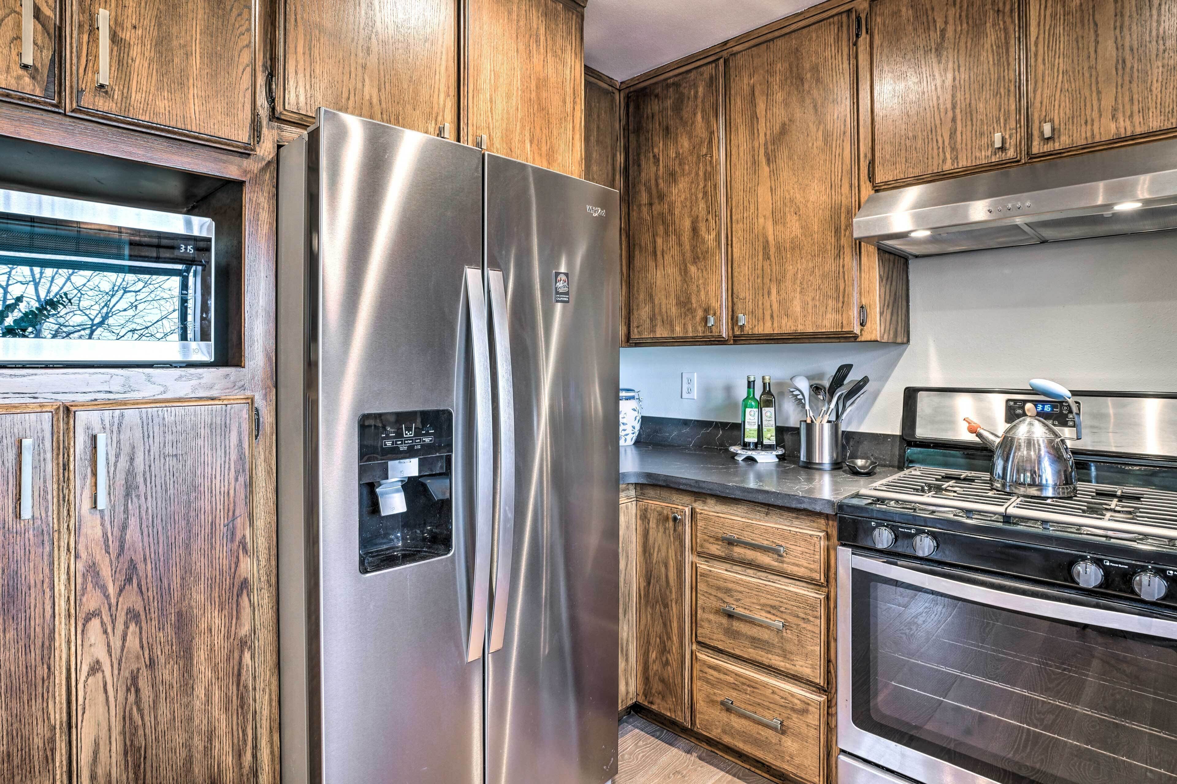 A kitchen with wooden cabinets, a stainless steel refrigerator, a stove, and a microwave.
