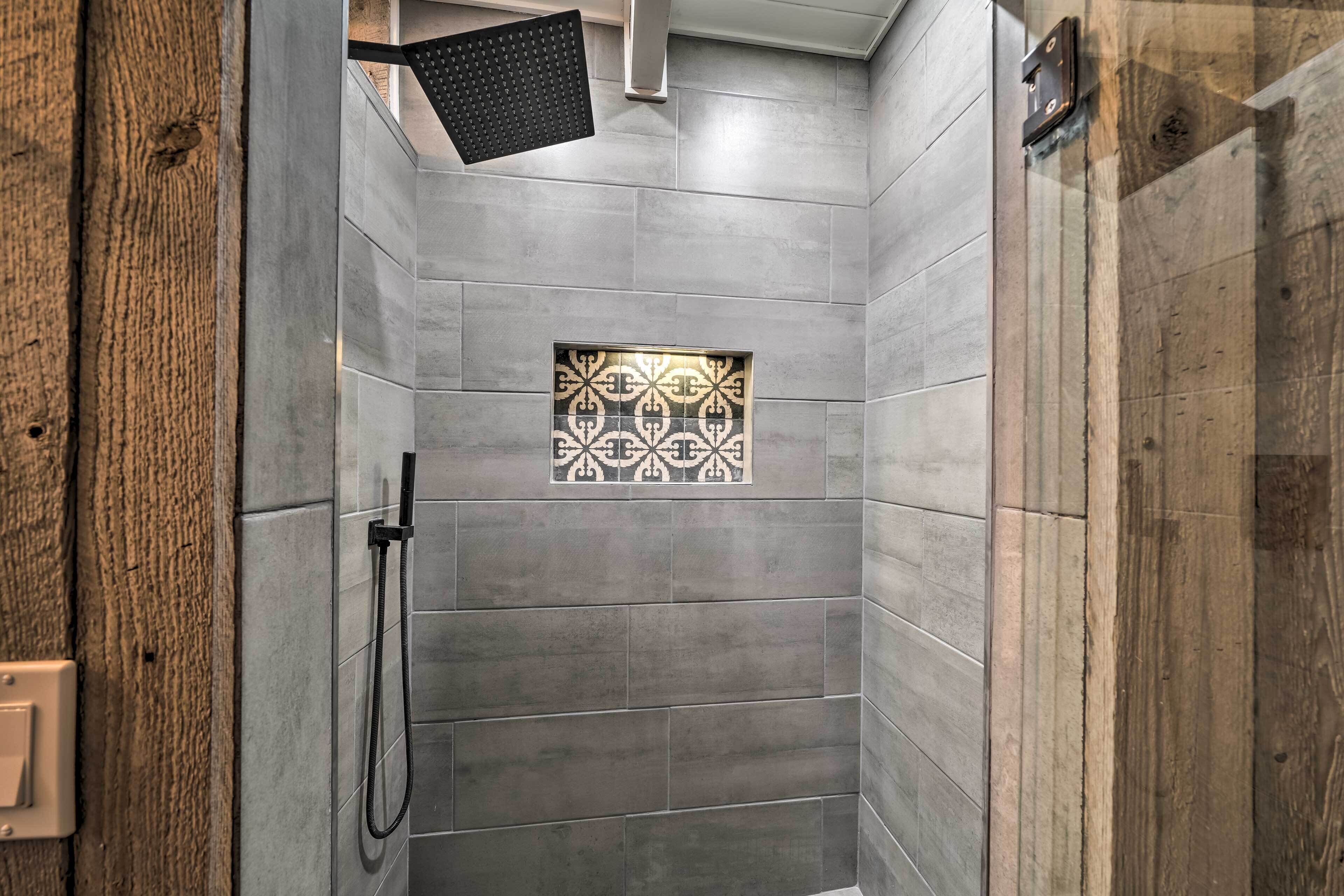 A shower with grey tiles and a decorative tile pattern in the center.