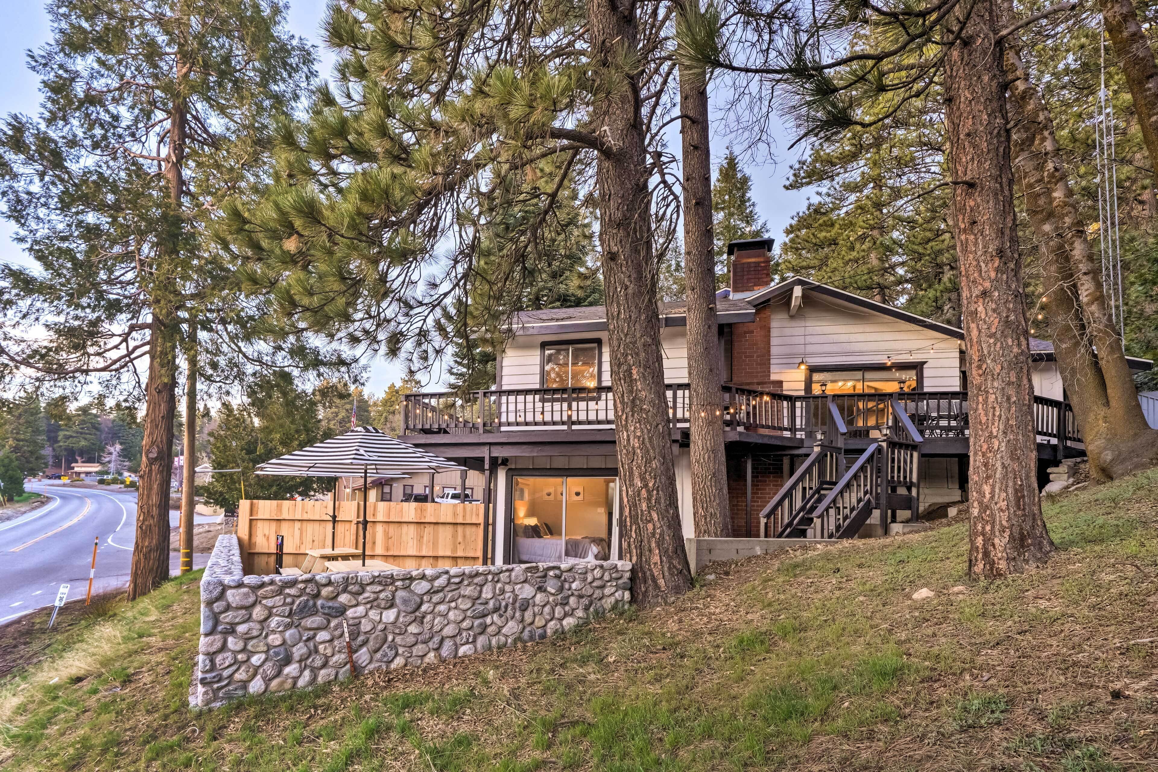 A two-story house with a stone wall, wooden deck, and a staircase leading to the upper level.