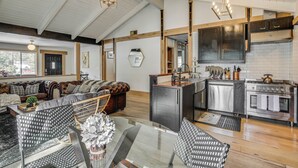 Un vaste espace de vie comprenant un canapé, une table à manger et une cuisine équipée d’appareils électroménagers modernes.