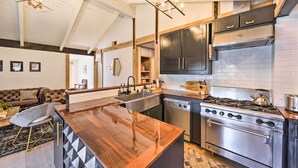 Une cuisine moderne dotée d’un îlot central, d’appareils électroménagers en acier inoxydable et d’un revêtement mural noir et blanc.