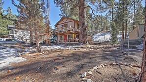 A lodge with a two-story structure, a balcony, and a snow-covered ground.