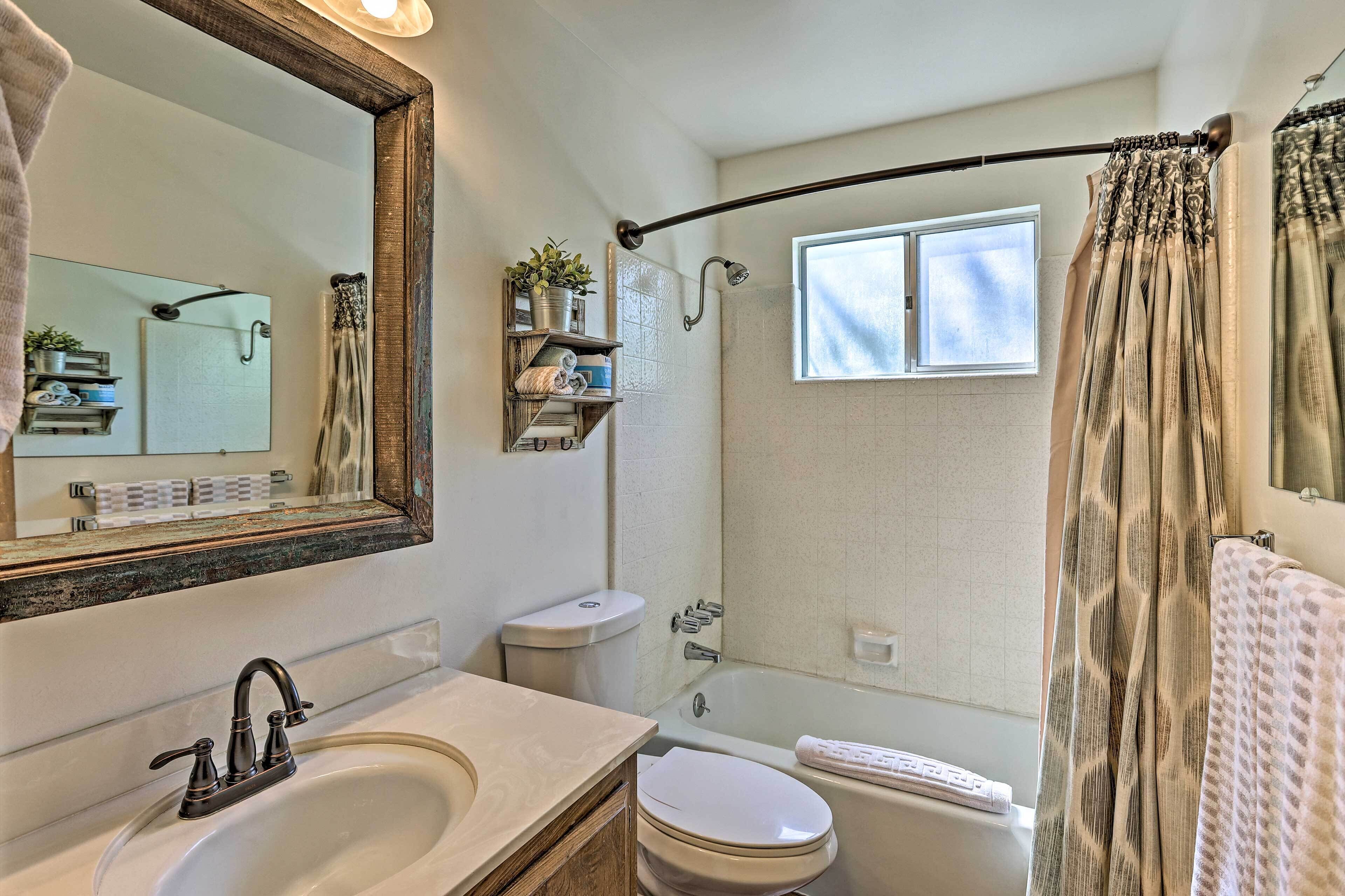 A bathroom with a large mirror, a sink, a toilet, a bathtub, and a shower.