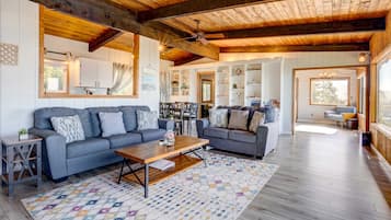 A spacious living room with a wooden ceiling, two sofas, a coffee table, and a patterned rug.