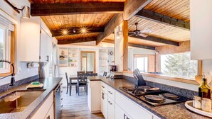 Une cuisine moderne dotée de plans de travail en granit, d’armoires blanches et d’un îlot central.